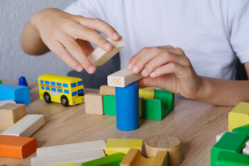 kid, boy builds towers and buildings from colored wooden figures, concept of housing construction, mortgage, insurance, happy childhood, children's games