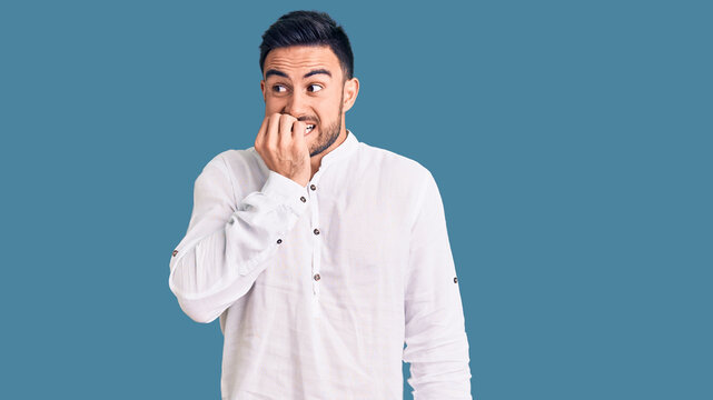 Young handsome man wearing casual clothes looking stressed and nervous with hands on mouth biting nails. anxiety problem.