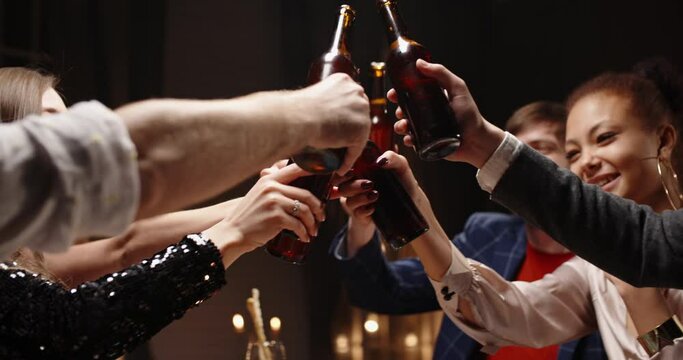 Group of happy friends having fun together, drinking beer and clinking their bottles, celebrating, happily smiling - friendship, recreational pursuit concept 4k footage