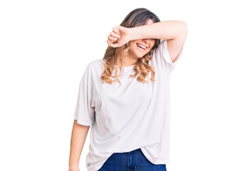 Young caucasian woman wearing casual clothes covering eyes with arm smiling cheerful and funny. blind concept.