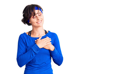 Beautiful young woman with short hair wearing training workout clothes smiling with hands on chest with closed eyes and grateful gesture on face. health concept.