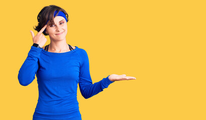 Beautiful young woman with short hair wearing training workout clothes confused and annoyed with...