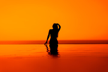 Silhouettes of girls on the pool at sunrise or sunset