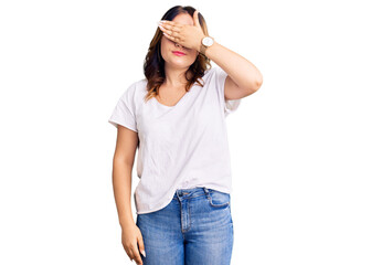 Young beautiful caucasian woman wearing casual white tshirt covering eyes with hand, looking serious and sad. sightless, hiding and rejection concept