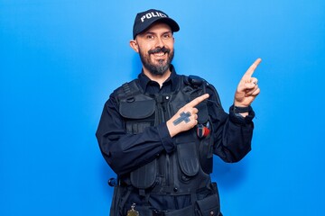 Obraz premium Young handsome man wearing police uniform smiling and looking at the camera pointing with two hands and fingers to the side.