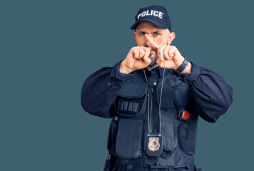 Young handsome man wearing police uniform rejection expression crossing fingers doing negative sign