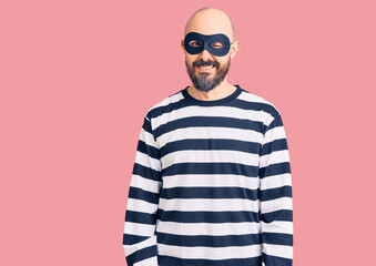 Young handsome man wearing burglar mask winking looking at the camera with sexy expression,...