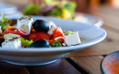 A Caesar salad on white plate on dark wooden table