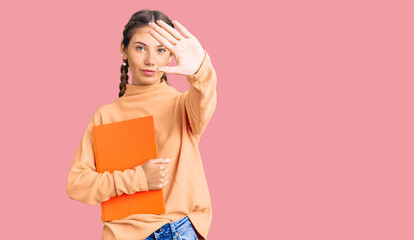 Beautiful caucasian woman with blonde hair holding book with open hand doing stop sign with serious and confident expression, defense gesture