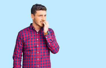 Handsome young man with bear wearing casual shirt looking stressed and nervous with hands on mouth biting nails. anxiety problem.