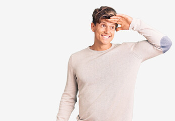 Young handsome man wearing casual clothes very happy and smiling looking far away with hand over head. searching concept.