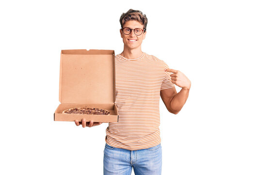Young handsome man holding delivery pizza box pointing finger to one self smiling happy and proud