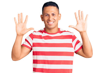 Young handsome latin man wearing casual clothes showing and pointing up with fingers number ten while smiling confident and happy.