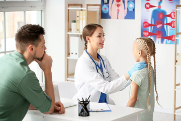 Doctor examining little girl with thyroid gland problem in clinic