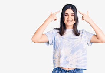 Young beautiful girl wearing casual t shirt smiling pointing to head with both hands finger, great idea or thought, good memory