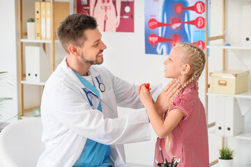 Doctor examining little girl with thyroid gland problem in clinic