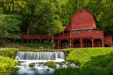 An old red grist mill with a small waterfall.