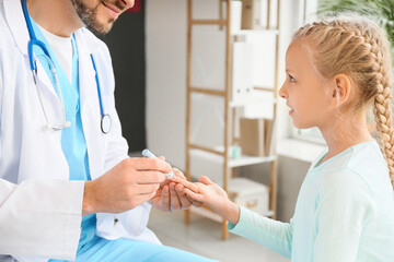 Doctor measuring blood sugar level of little girl in clinic