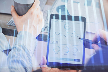 Double exposure of man's hands holding and using a phone and financial chart drawing. Market analysis concept.