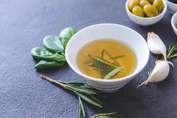 Bowl of rosemary oil on dark background