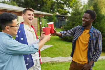 Waist up portrait of multi-ethnic group of men drinking beer while enjoying outdoor party in Summer for Independence day