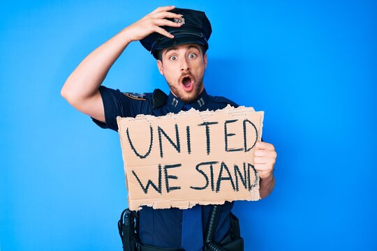Young caucasian man wearing police uniform holding united we stand banner stressed and frustrated with hand on head, surprised and angry face