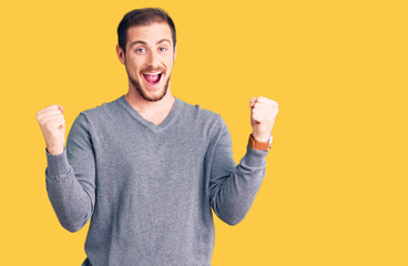 Young handsome caucasian man wearing casual winter sweater screaming proud, celebrating victory and success very excited with raised arms