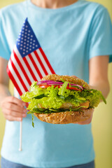 Woman with tasty vegan burger and flag of USA, closeup