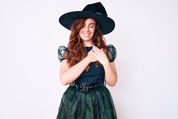 Young beautiful woman wearing witch halloween costume smiling with hands on chest with closed eyes and grateful gesture on face. health concept.