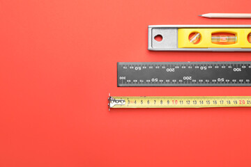 Measuring tape with builder's supplies on color background
