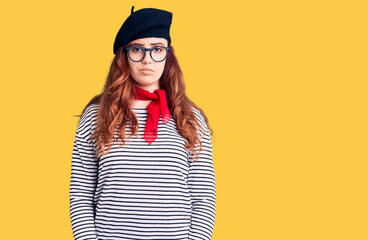 Young beautiful woman wearing french look with beret with serious expression on face. simple and natural looking at the camera.