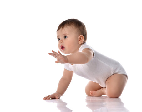 Little baby girl toddler in diaper and white blank body suit crawling on floor and looking up at the corner isolated on white 