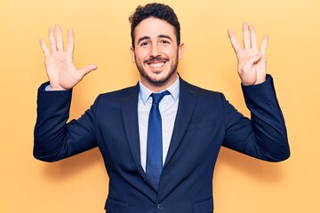 Young hispanic man wearing suit showing and pointing up with fingers number nine while smiling confident and happy.