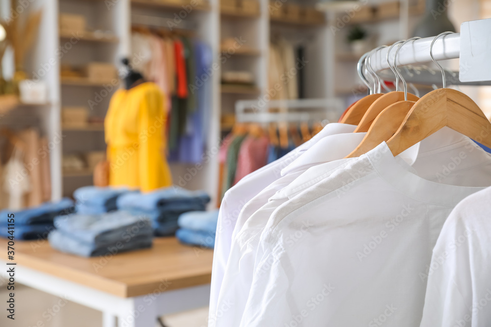 Wall mural hanger with stylish clothes in modern store, closeup