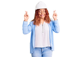 Young latin woman wearing architect hardhat gesturing finger crossed smiling with hope and eyes closed. luck and superstitious concept.