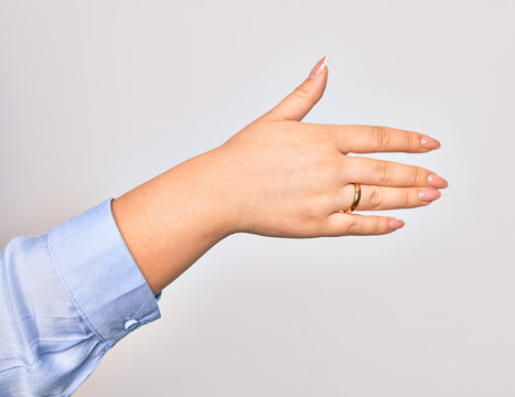 Hand of caucasian young woman holding golden marriage ring over isolated white background