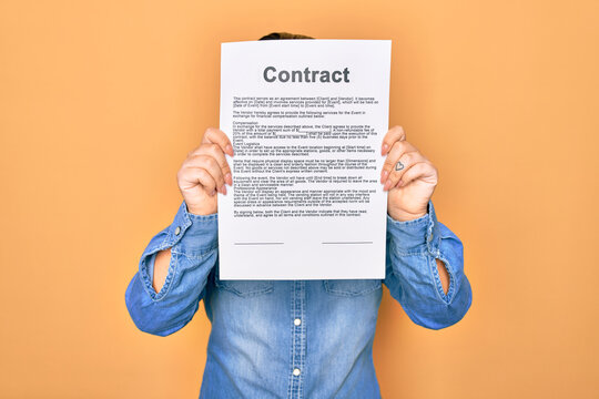 Woman holding contract document paper standing over isolated yellow background