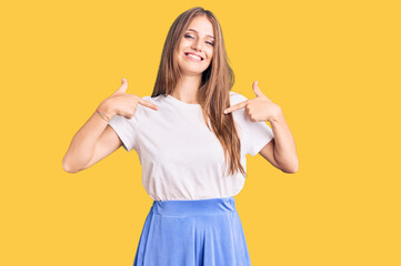 Young beautiful blonde woman wearing summer style looking confident with smile on face, pointing...