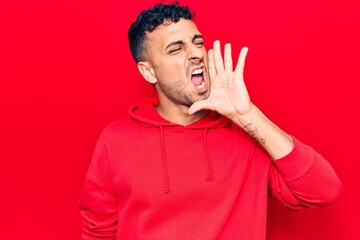 Young hispanic man wearing casual clothes shouting and screaming loud to side with hand on mouth. communication concept.