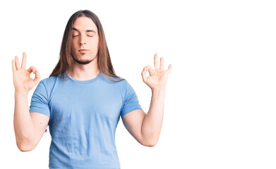 Obraz na płótnie Canvas Young adult man with long hair wearing casual clothes relax and smiling with eyes closed doing meditation gesture with fingers. yoga concept.