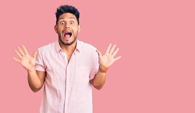 Handsome latin american young man wearing casual summer shirt celebrating crazy and amazed for success with arms raised and open eyes screaming excited. winner concept