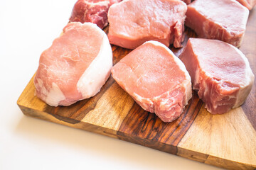 Boneless raw pork loin chops close up on wooden cutting board