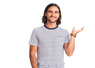 Young handsome man wearing casual clothes smiling cheerful presenting and pointing with palm of hand looking at the camera.