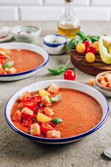 Spanish summer cold soup gazpacho with vegetables on concrete background.