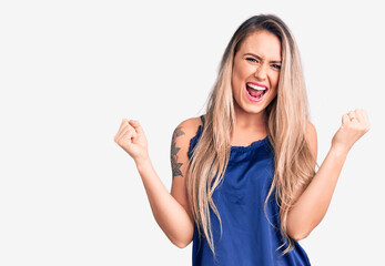 Young beautiful blonde woman wearing casual sleeveless t-shirt screaming proud, celebrating victory...