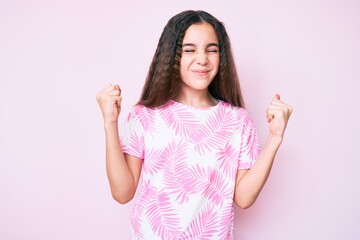 Cute hispanic child girl wearing casual clothes very happy and excited doing winner gesture with arms raised, smiling and screaming for success. celebration concept.