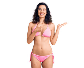 Obraz premium Young beautiful hispanic woman wearing bikini showing palm hand and doing ok gesture with thumbs up, smiling happy and cheerful