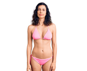 Fototapeta premium Young beautiful hispanic woman wearing bikini relaxed with serious expression on face. simple and natural looking at the camera.