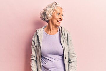 Senior grey-haired woman wearing casual sporty clothes looking away to side with smile on face,...