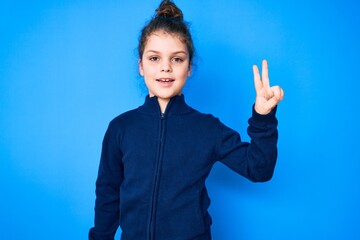 Cute hispanic child wearing casual clothes smiling with happy face winking at the camera doing victory sign. number two.